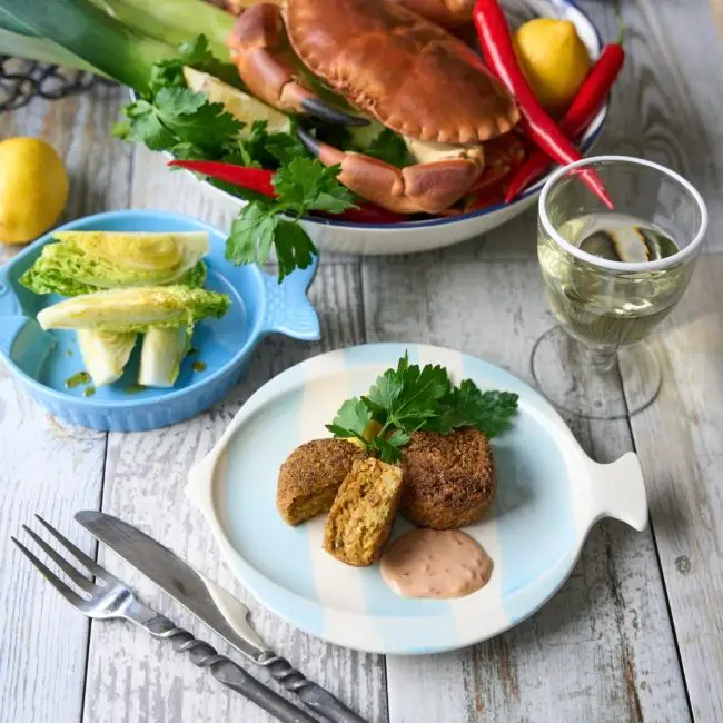 Crabbie crabcakes on a plate with a crab in the background